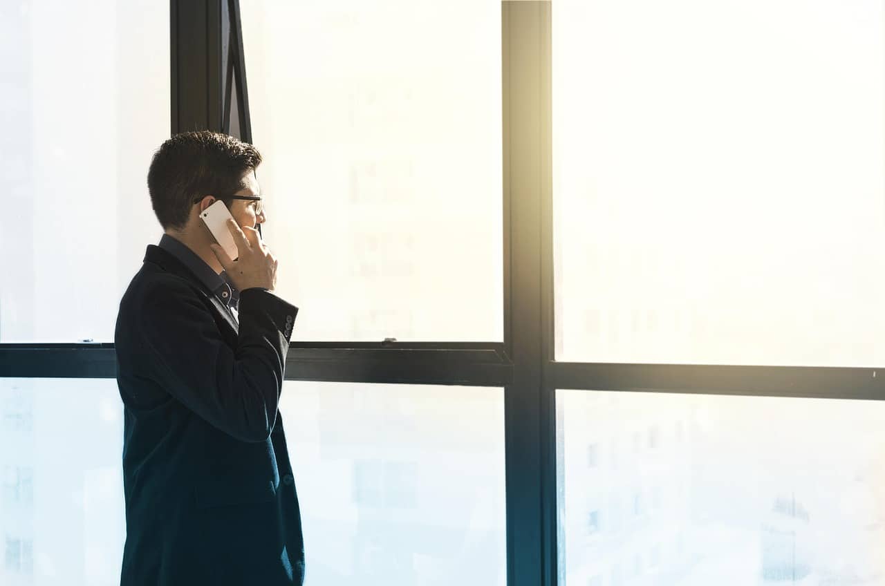 Businessman talking on the phone by a large office window